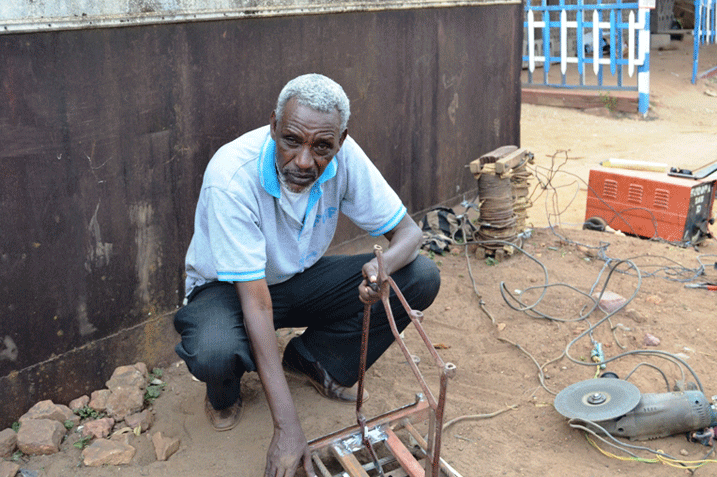 Uyu musaza, Nyirisenge Jean George, w'imyaka w'imyaka 75 avuga ko kugira amashanyarazi byatumye ashobora gukora imyuga no kuyigisha abakiri bato. Aha, arimo gusudira amaguru y'icyarahani.