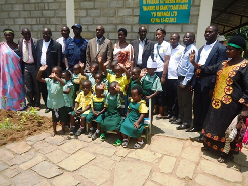 Abayobozi, abarezi, ababyeyi n'abana bafashe ifoto y'urwibutso.