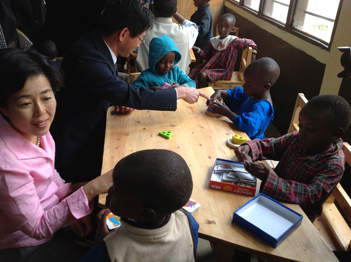 Ambasaderi Kazuya n'umufasha we bari kumwe n'abana bo mu irerero ry'abana b'incuke mu nkambi ya Kigeme.