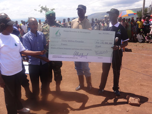 Umuyobozi wa BRD (iburyo) ashyikiriza umunyamabanga uhoraho muri MIDIMAR (ukurikiyeho) sheke ya miliyoni 30 azakoreshwa mu kubakira Abanyarwanda birukanwe muri Tanzaniya.