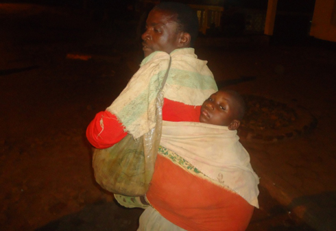 Kubwimana Gaspal avuye gusabiriza n'umwana mu mugongo.