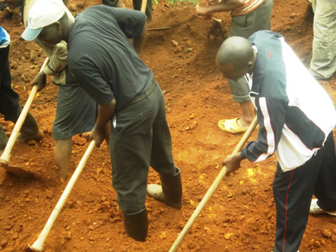 Minisitiri Kamanzi (wambaye ingofero) n'umuyobozi w'akarere ka Rutsiro bifatanyije n'abaturage mu guhanga umuhanda mushya.