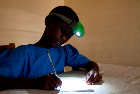 Umunyeshuri arimo gusubira mu masomo nijoro yifashishije urumuri rw'itara rya NURU.