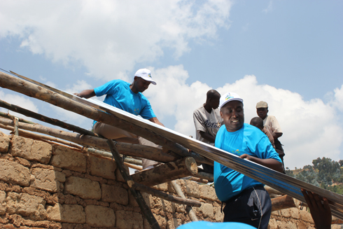 Abakozi b'ikigo cy'imisoro n'amahoro bubaka inzu ya Hakizimana Théogène mu karere ka Nyabihu.