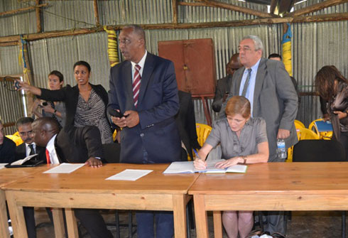 Sayinzoga Jean, umuyobozi wa komisiyo yo gusubiza mu buzima busanzwe abahoze ku rugerero hamwe na Ambasaderi Power uri kwandika mu gitabo cy'abashyitsi.