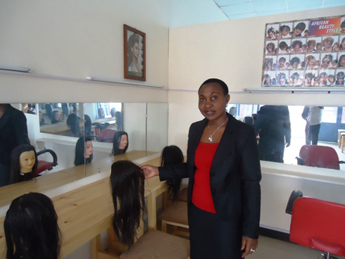 Niyigena Alfonsine yerekana imfashanyigisho ziri mu ishuri rye ryigisha gutunganya ubwiza.