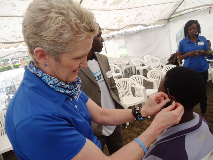 Umwe mu baganga ba Starkey Hearing Foundation ashyira akunganira kumva mu matwi y'umurwayi.