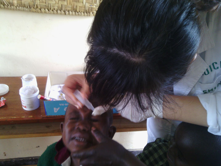 Umwe mu bakorerabushake ashyirira umwana umuti mu maso.