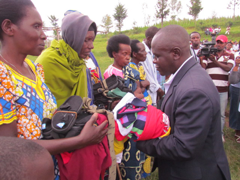 Umuyobozi w'akarere ka Gicumbi ashyikiriza abarokotse imyenda yo kwambara yatanzwe na World Vision.