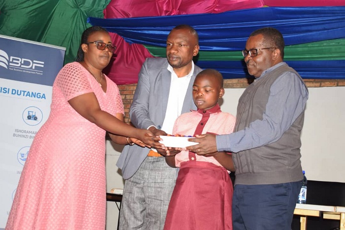 Vincent Munyeshyaka Umuyobozi w'Ikigo BDF(iburyo) ashyikiriza umwe mu bana ibikoresho by'ishuri