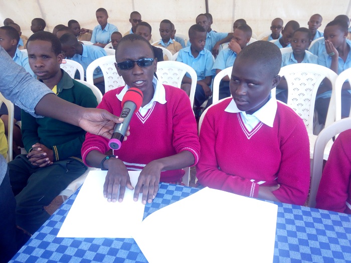 Umwe mu bana asoma umwandiko we