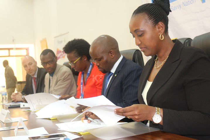 Abayobozi banyuranye bashyira umukono ku masezerano ajyanye n'iyi nguzanyo ya mudasobwa.