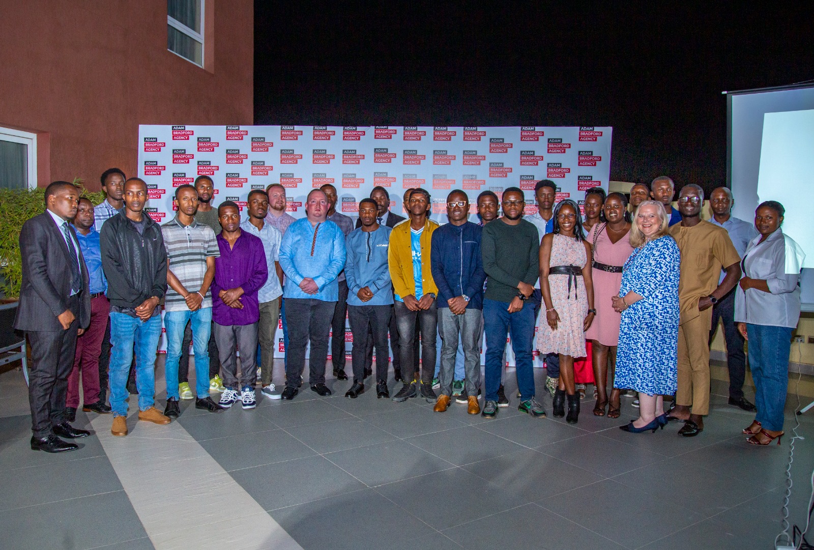 Adam Bradford (uri hagati wambaye ishati y'ubururu) hamwe n'abafatanyabikorwa be ndetse n'inshuti ze bahuriye mu birori byo kwishimira umwaka amaze akorera mu Rwanda