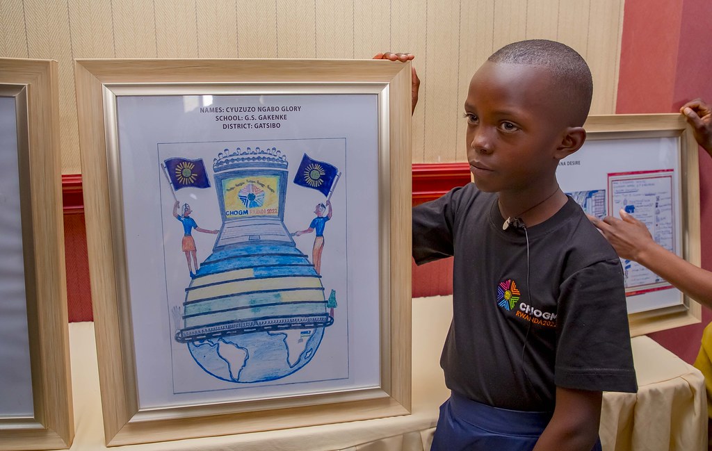 Cyuzuzo Ngabo Glory wo mu Karere ka Gatsibo w'imyaka icyenda y'amavuko, yashushanyije ishusho y'agacuma kazwi mu muco nyarwanda nk'igikoresho cy'ingenzi. Asobanura ko igice cyako cyo hasi kigaragara mu ishusho y'isi bisobanuye uburyo umuryango wa Commonwealth ugera ku isi hose. Hagaragaraho kandi ibisa n'intebe 54 bisobanuye ibihugu byose bigize uwo muryango. Hagaragaraho n'inyubako izwi nka Kigali Convention Centre izakira iyo nama, mudasobwa igaragaza guteza imbere ikoranabuhanga n'ubumenyi muri uwo muryango. Hejuru hariho ishusho y'ikamba ivuga umuyobozi w'uwo muryango ari we Umwamikazi w'u Bwongereza, Elisabeth II, ku mpande hakaba n'amashusho y'urubyiruko rufite amabendera ya Commonwealth, bisobanuye imbaraga z'urubyiruko muri uyu muryango