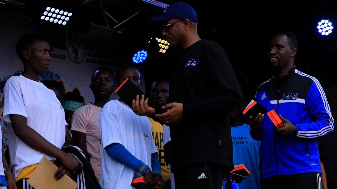 Umuyobozi w'Akarere ka Bugesera, Richard Mutabazi hamwe na Pasiteri Ndizeye bahemba Bibiliya abana batsinze amarushanwa yo gusiganwa