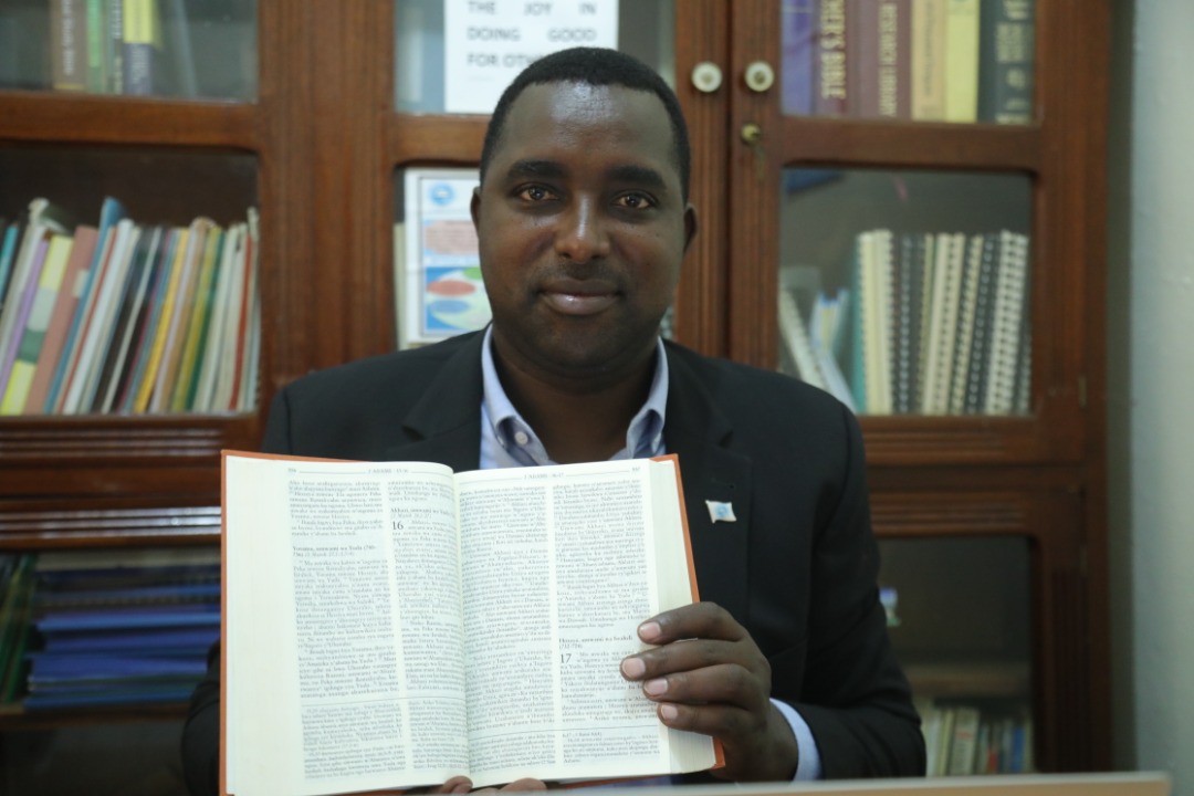 Bibiliya mu biganza bya Pasiteri Gasare Michael, yanditswe ku mpapuro zikozwe mu ifu y'uruhu rw'inyamaswa n'ibiti byo ku nyanja