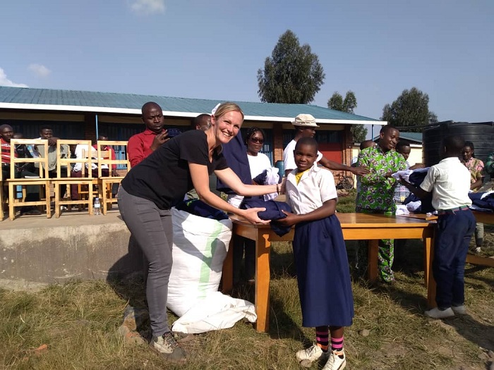 INGRID BAAS, Umuyobozi wa Wilderness Safaris mu Rwanda ashyikiriza abana imyambaro y'ishuri