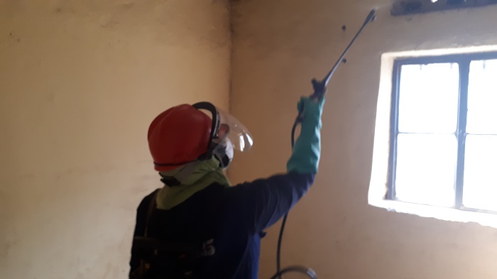 Umujyanama w'ubuzima ari mu gikorwa cyo gutera umuti wica imibu mu nzu