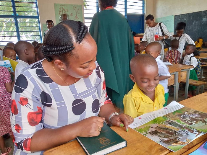 Esperance Nshutiraguma Umuyobozi wungirije wa Nyarugenge areba uko umwana asoma igitabo yahawe
