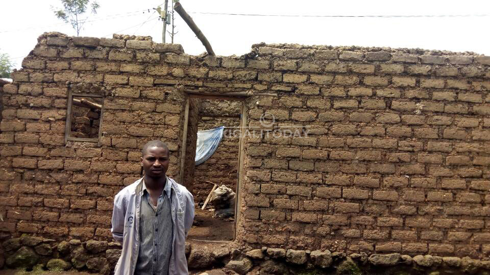 Uyu mugabo ahagaze imbere y'inzu ye yasenyutse 