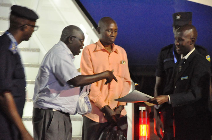 Umukozi wa Uganda ukora mu biro by'abinjira n'abasohoka (uwa kabiri ibumoso) yakira impapuro zemeza ko Birindabagabo (wambaye amapingu) yakiriwe n'u Rwanda.