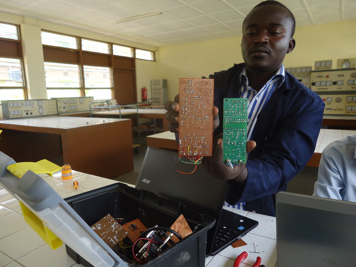 Kazungu Robert yerekana plaquette akora twakwita nk'umutima wa buri gikoresho cy'ikoranabuhanga nka mudasobwa, radio, camera n'ibindi. Iyi icyatsi ni iyakorewe mu nganda zikomeye mu gihe iyi yindi ari we wayikoreye.