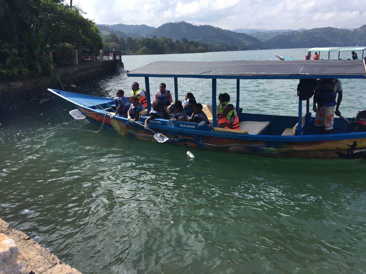 Abanyeshuri mu bwato barimo gukura imyanda mu mazi y