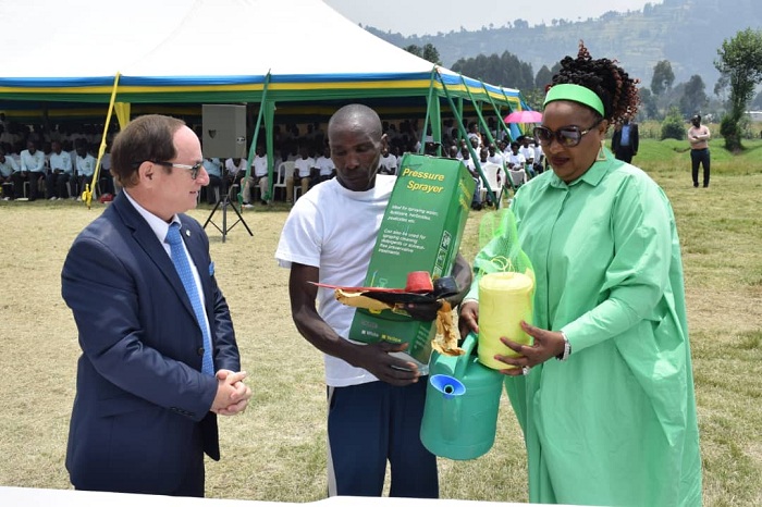 Ambasaderi Ron Adam, hamwe na Nyirahabineza Valérie bashyikiriza umwe mu batahutse urangije amasomo y'imyuga