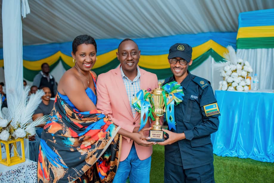 Uhagarariye Umudugudu wa Mwijuto (hagati) yashyikirijwe igikombe cy'ishimwe kubera ibikorwa by'indashyikirwa