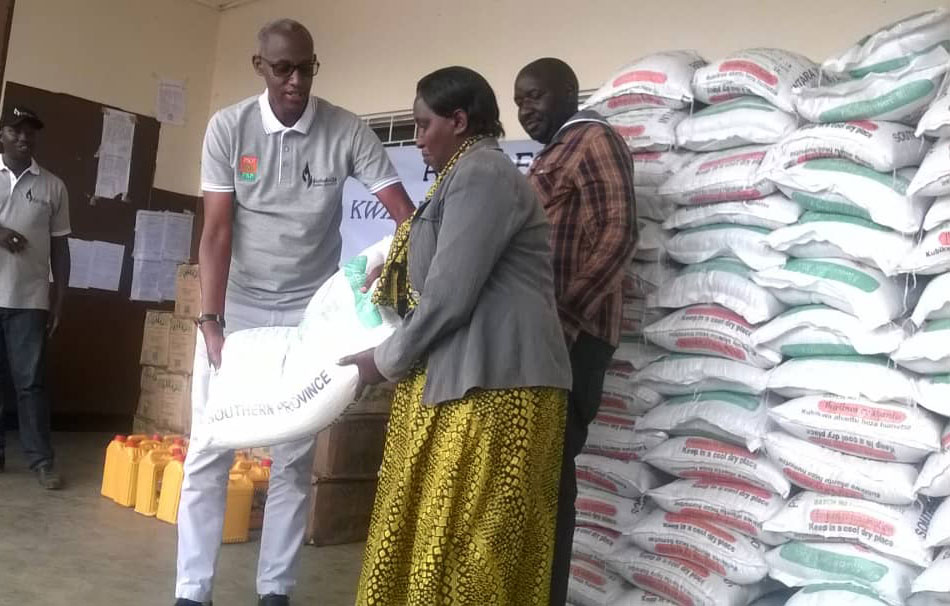 Ruzibiza Steven umuyobozi wa PSF ashyikiriza ibiribwa umwe mu batishoboye bubakiwe aya mazu