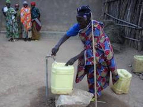 Umukecuru ari kuvoma amazi kuri robine imaze gushyirwa mu mudugudu.