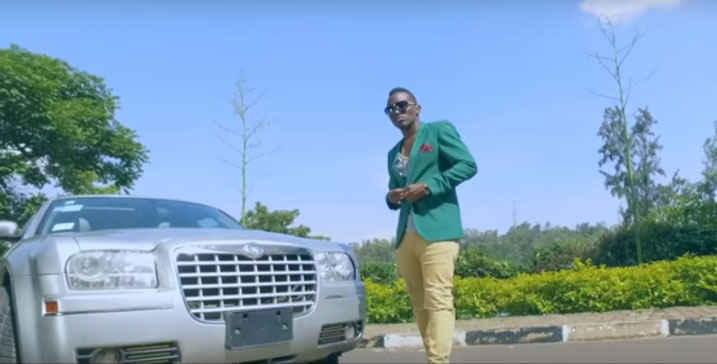 Tom Close mu mashusho y'indirimbo "Ferrari", aba ahagaze imbere y'imodoka nziza izwi nka Chrysler.