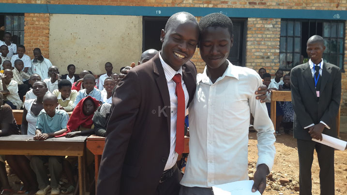 Umuyobozi wa ES Mutima, Nizeyimana Francois, ashimira umwe mu banyeshuri batsinze neza bakanabona buruse.