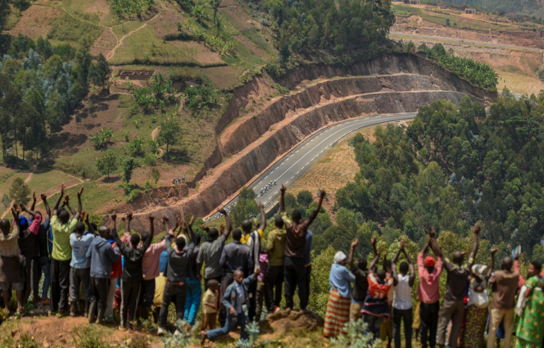 Abaturage bari bihagarariye ku mpinga z'imisozi bakurikiranye uko amagare anyerera kuri kaburimbo