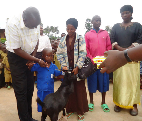 Umuyobozi wa World Vision mu Ntara y'Amajyaruguru ashyikiriza impano umwana. (Foto: L. Nshimiyimana)